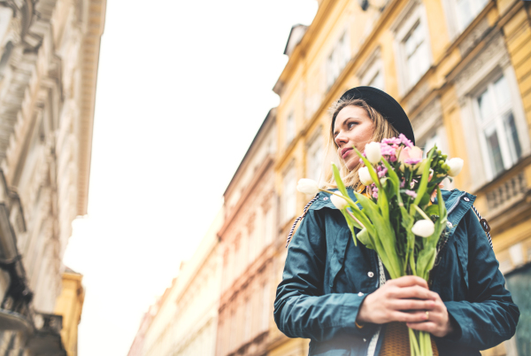 Portrait of a young beautiful woman with flowers in town. Sunny spring. Copy space.