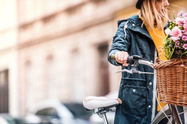 Young woman with bicycle in sunny spring town. Copy space.