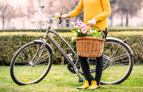 Unrecognizable young woman with bicycle standing outside in sunny spring town.