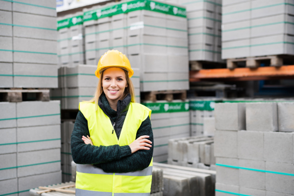 Female worker standing outside a warehouse, arms crossed. Woman in an industrial area.