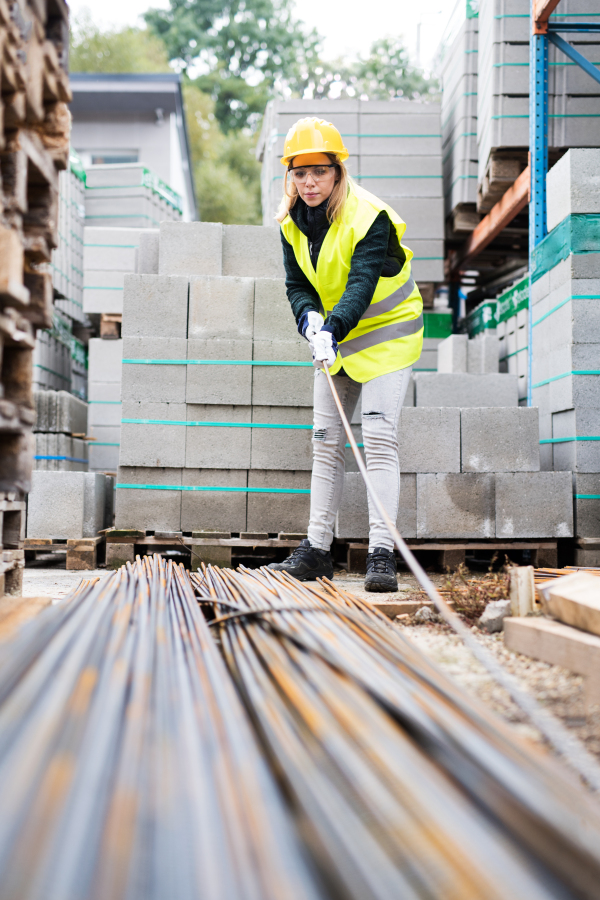 Female worker in an industrial area. Beautiful young woman working outside warehouse building.