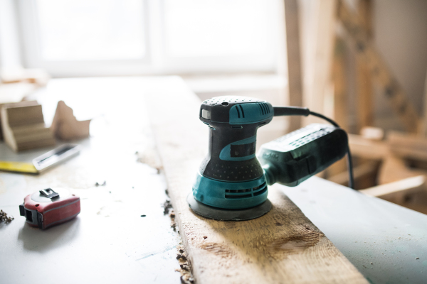 Angle grinder in carpenter workroom. Electric tool and tape measurer on the table.