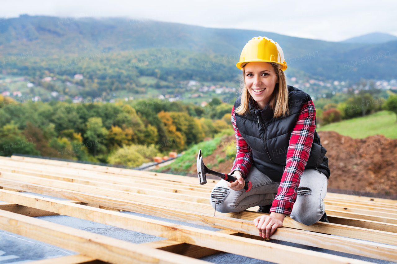 Female worker on the building site. Young woman working as a roofer. House construction.