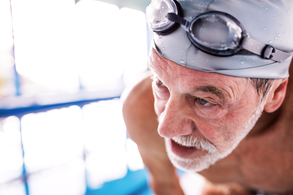 Senior man in an indoor swimming pool. Active pensioner enjoying sport. Close up.