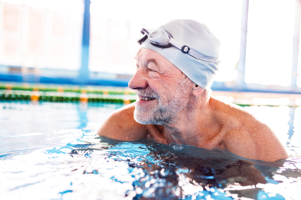 Senior man in an indoor swimming pool. Active pensioner enjoying sport.