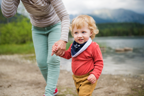 Unrecognizable senior woman with a happy little boy at the lake, summer day.