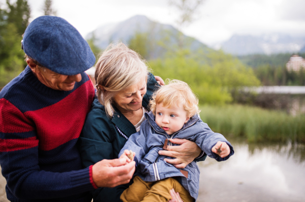 Senior couple with little boy at the lake, having fun.