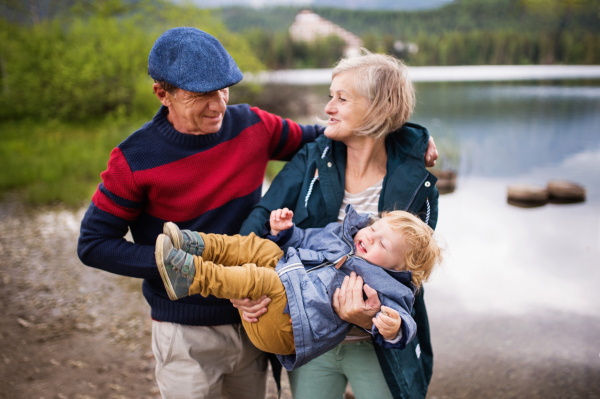 Senior couple with little boy at the lake, having fun.