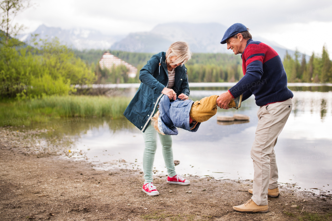 Senior couple with little boy at the lake, having fun.