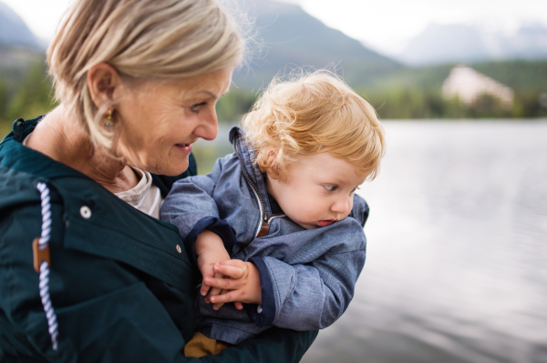 Senior woman with little boy at the lake. Grandmother with her grandson in the nature.