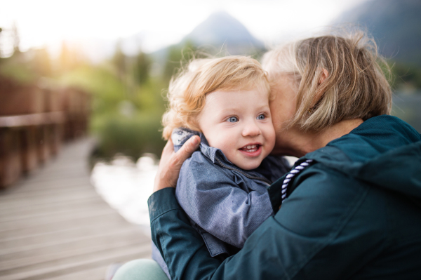 Senior woman with little boy at the lake. Grandmother with her grandson in the nature.