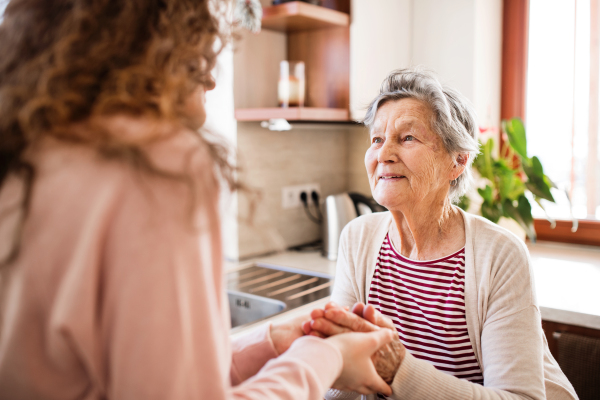 An unrecognizable teenage girl with grandmother at home. Family and generations concept.