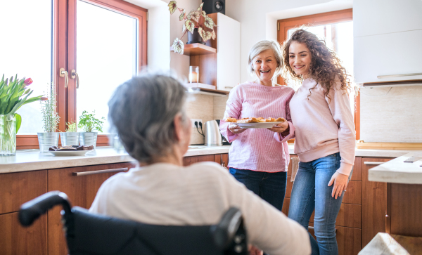 A teenage girl with her mother and grandmother in wheelchair at home. Family and generations concept.