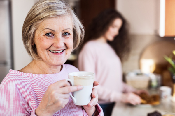 A teenage girl with mother or grandmother in the kitchen at home. Family and generations concept.