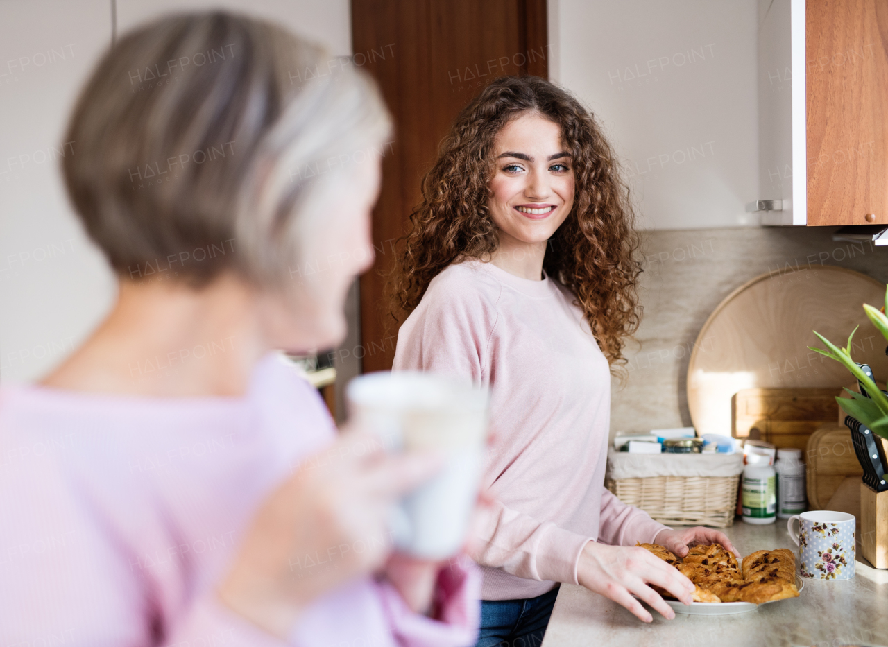 A teenage girl with mother or grandmother in the kitchen at home. Family and generations concept.