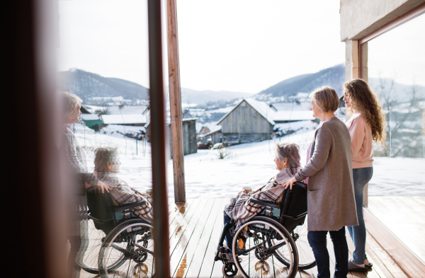 A teenage girl with her mother and grandmother in wheelchair at home. Family and generations concept.