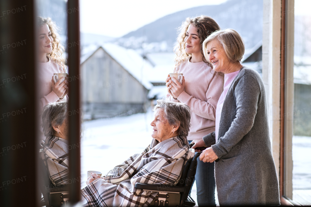 A teenage girl with her mother and grandmother in wheelchair at home. Family and generations concept.