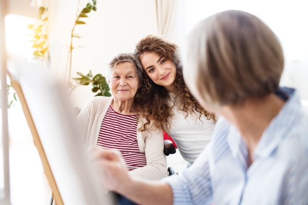 A teenage girl with her mother and grandmother in wheelchair at home. Family and generations concept.