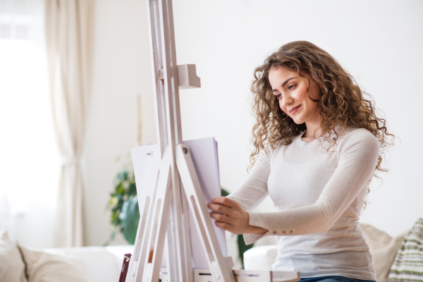 A happy teenage girl painting a picture at home.