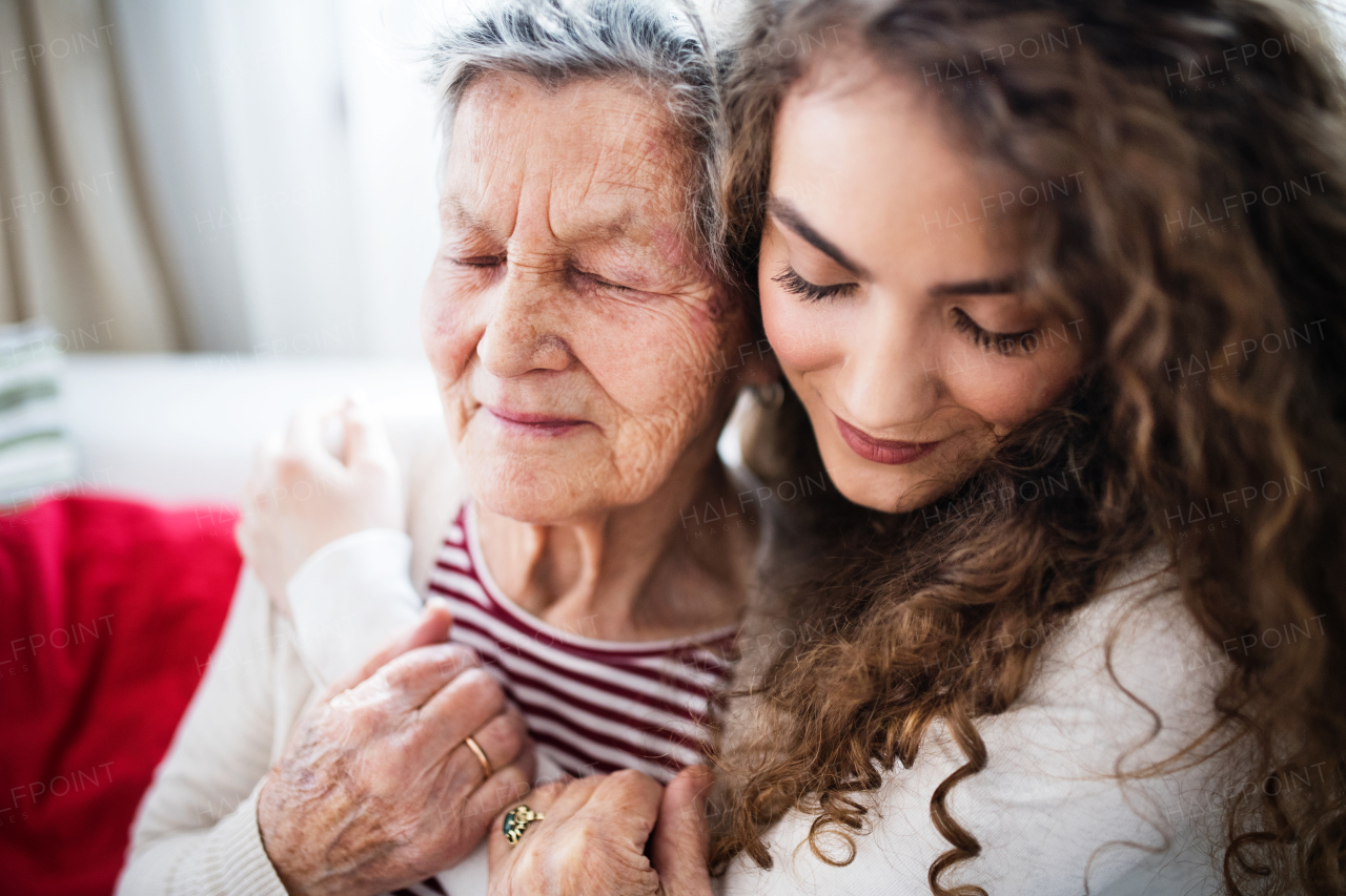 A teenage girl with grandmother at home, hugging. Family and generations concept.