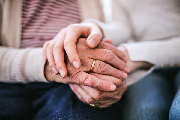 Unrecognizable teenage girl with grandmother at home, holding hands. Family and generations concept. Close up.