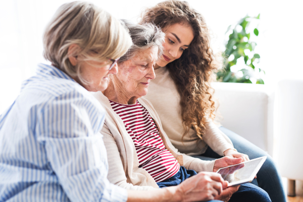 A teenage girl, her mother and grandmother with tablet at home. Family and generations concept.