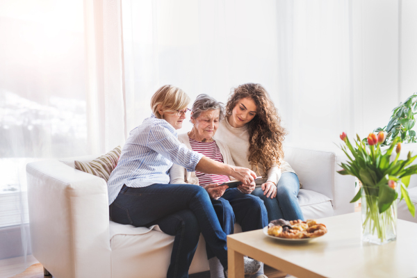 A teenage girl, her mother and grandmother with tablet at home. Family and generations concept.