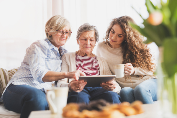 A teenage girl, her mother and grandmother with tablet at home. Family and generations concept.