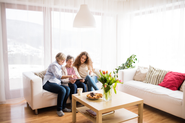 A teenage girl, her mother and grandmother with tablet at home. Family and generations concept.