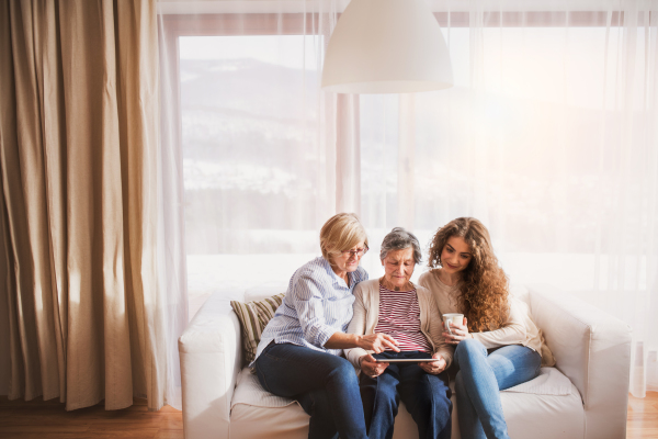 A teenage girl, her mother and grandmother with tablet at home. Family and generations concept.