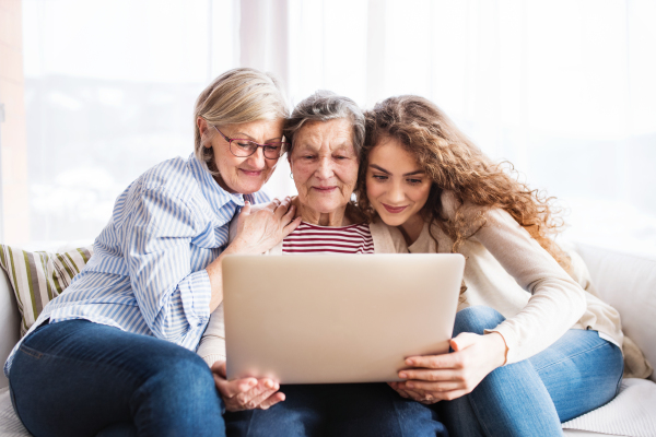 A teenage girl, her mother and grandmother with laptop at home. Family and generations concept.