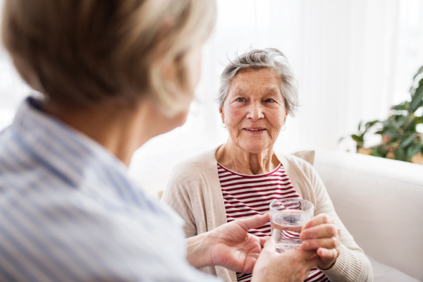 Two senior women at home,holding a glass of water. Family and generations concept.