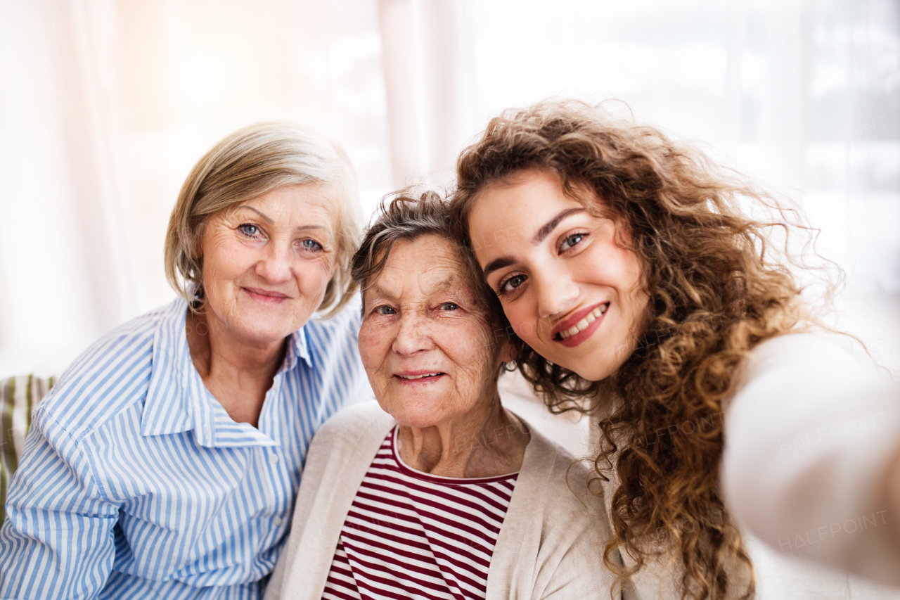 A teenage girl with her mother and grandmother at home. Family and generations concept.