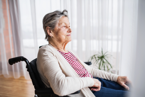 Senior woman in wheelchair at home looking out of the window.