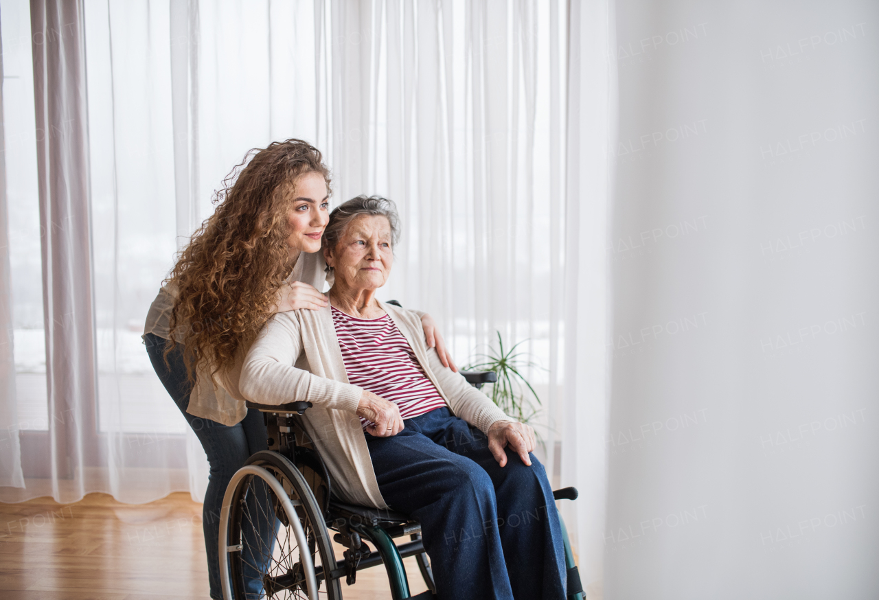 A teenage girl with grandmother at home, hugging. Family and generations concept.