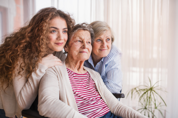 A teenage girl with her mother and grandmother in wheelchair at home. Family and generations concept.