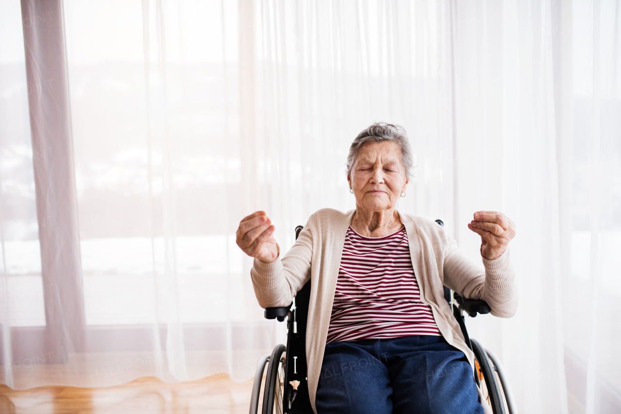 Senior woman in wheelchair at home, meditating.