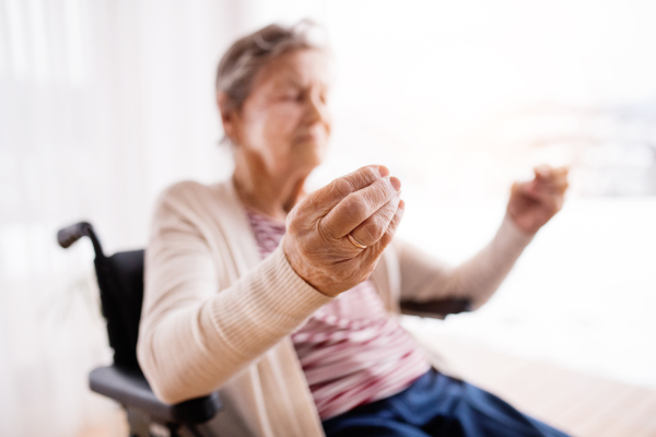 Senior woman in wheelchair at home, meditating.