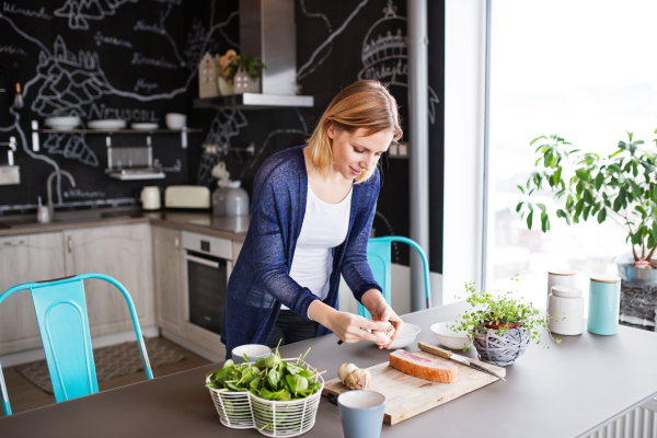 Beautiful young woman in the kithcen at home, cooking.