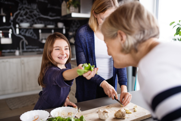 A small girl with her mother and grandmother at home, cooking. Family and generations concept.