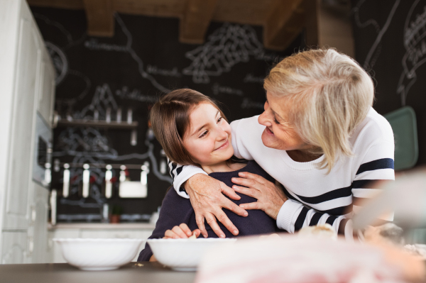 A small girl with her grandmother at home, cooking. Family and generations concept.