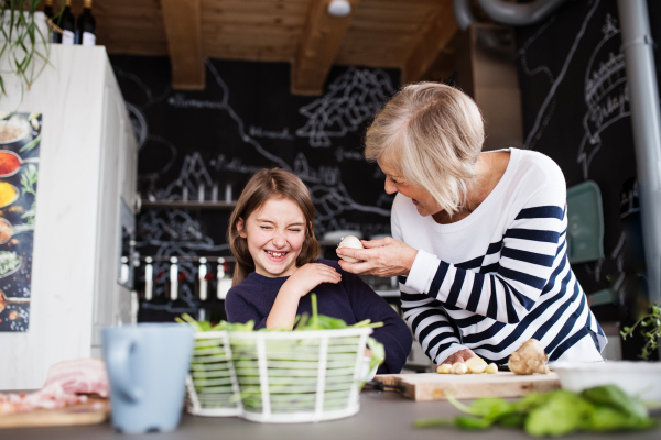 A small girl with her grandmother at home, cooking. Family and generations concept.