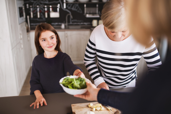 A small girl with her mother and grandmother at home, cooking. Family and generations concept.