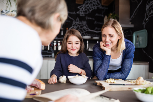 A small girl with her mother and grandmother at home, cooking. Family and generations concept.