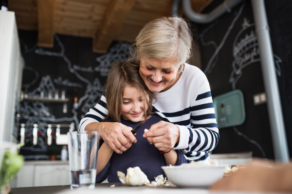 A small girl with her grandmother at home, cooking. Family and generations concept.