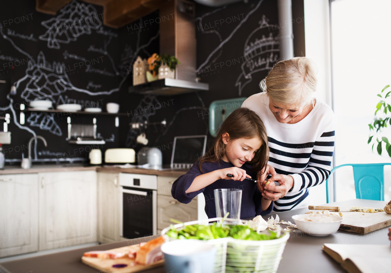 A small girl with her grandmother at home, cooking. Family and generations concept.