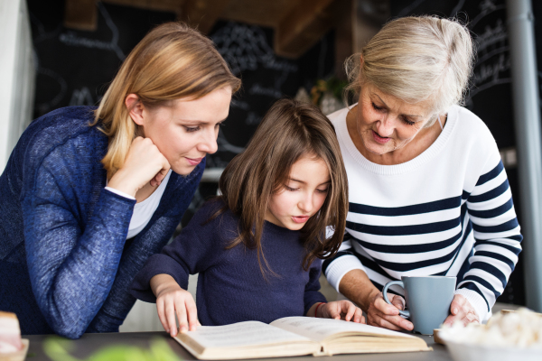 A small girl with her mother and grandmother at home. Family and generations concept.