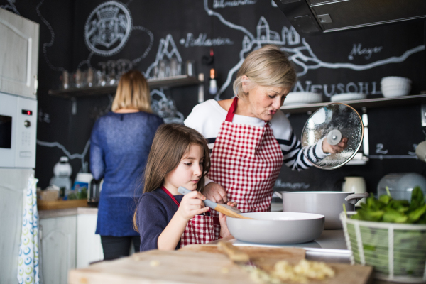 A small girl with her mother and grandmother at home, cooking. Family and generations concept.