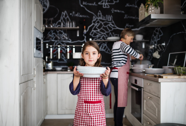 A small girl with grandmother at home, cooking. Family and generations concept.