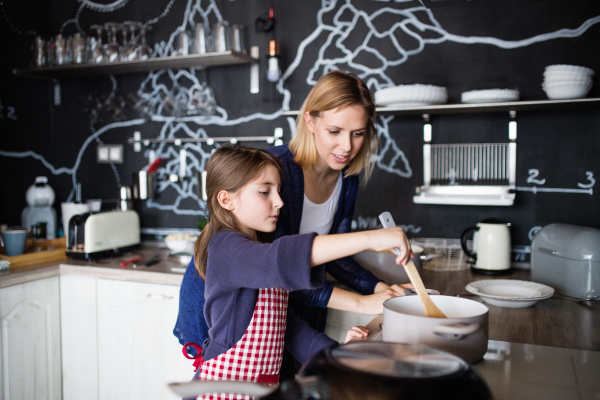 A small girl with her mother at home, cooking. Family and generations concept.